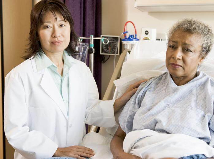 mujer en la cama de un hospital con un médico a su lado
