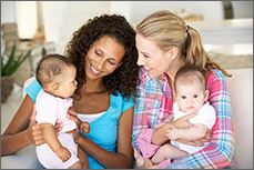 Two women holding babies and chatting