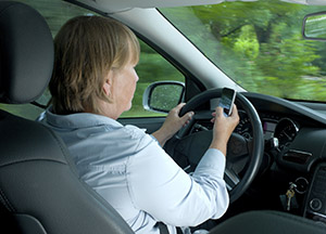 Mujer conduciendo y enviando un mensaje de texto