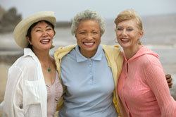Tres mujeres mayores sonriendo en la playa