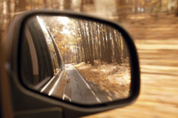 The sideview mirror of a car reflecting the road behind.