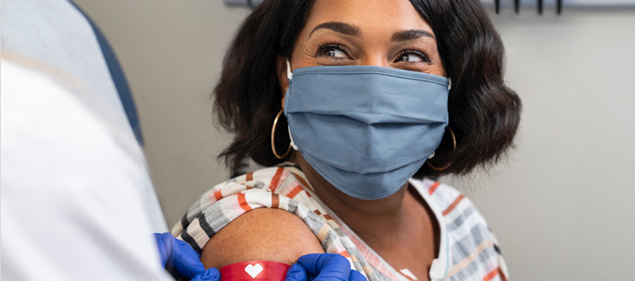 Mujer con máscara mientras recibe la vacuna contra el COVID-19 
