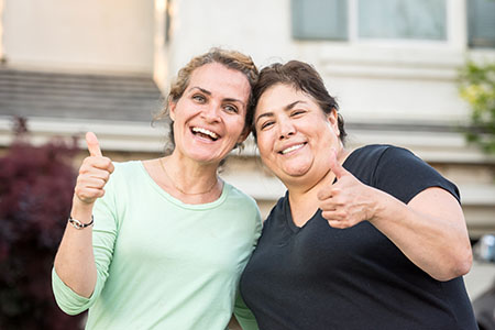 Two women making a thumbs-up gesture