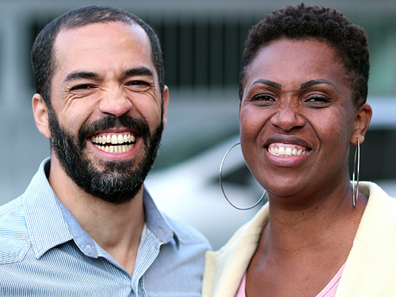 A smiling couple is standing close together outdoors. 